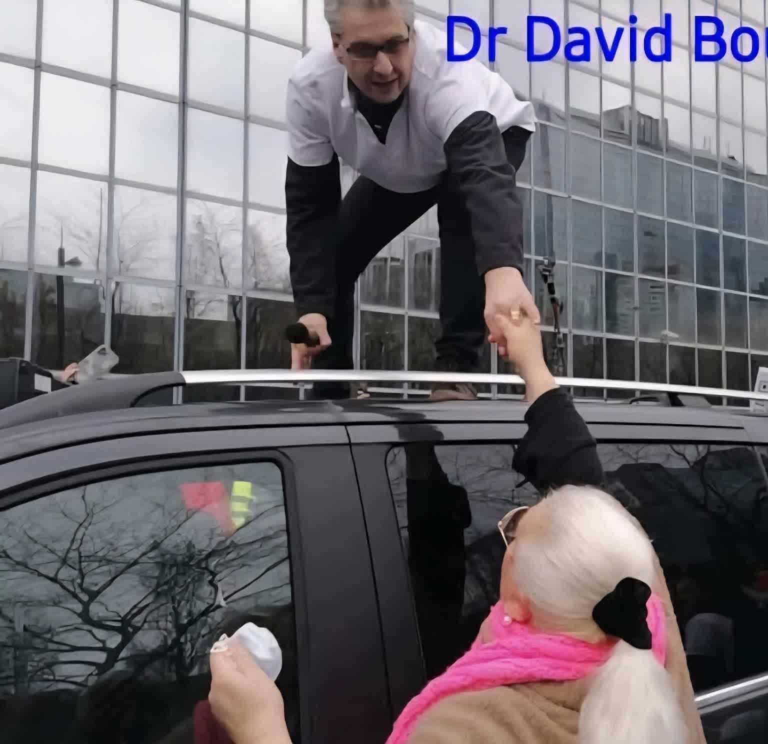 Le Dr David Bouillon tend la main à une personne âgée lors d'une action de terrain